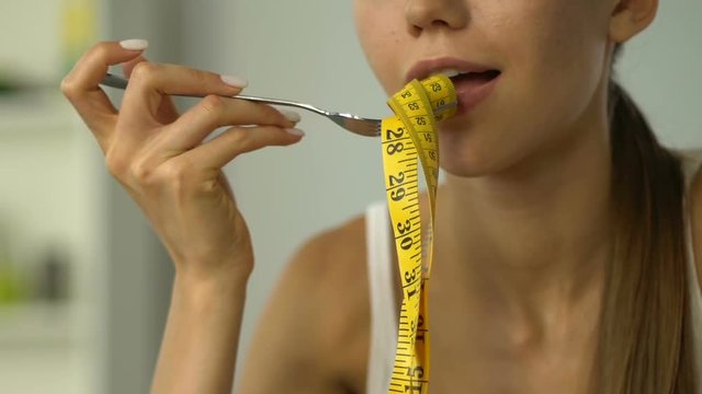 Anorexic girl eating measuring tape, concept of dependence on calorie counting