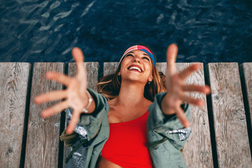 Young happy woman laying on the dock with arms raised