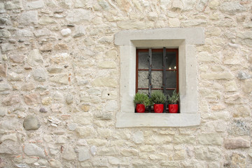Stone window with spice plants in red pots