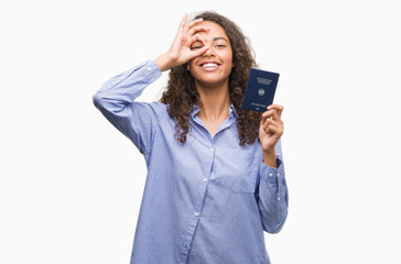 Naklejka premium Young hispanic woman holding passport of Germany with happy face smiling doing ok sign with hand on eye looking through fingers