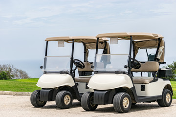 Two empty white golf carts parked beside each other on the driveway of a golf course in Montego Bay, Jamaica.