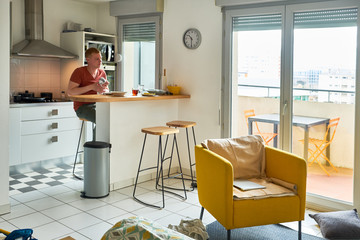 Happy mature man drinking coffee while having tasty breakfast at the kitchen table