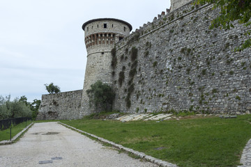 Fototapeta na wymiar Wall and a tower from outside Brescia castle with a cloudy sky in background