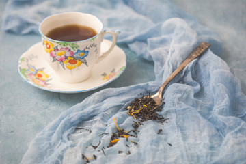 Bell Fine Bone China Tea Cup and Saucer on Blue Background with Spoon of Ginger Peach Herbal Tea Beside