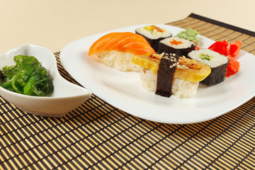 Assorted sushi and rolls and chuka salad on a bamboo mat close up.