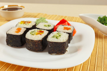 Sushi set, hiyashi wakame salad and soy sauce with ginger and wasabi on a bamboo mat close up.