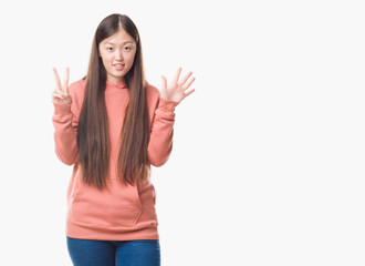 Young Chinese woman over isolated background wearing sport sweathshirt showing and pointing up with fingers number seven while smiling confident and happy.