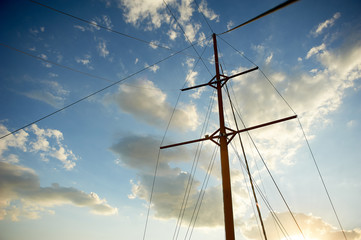 Fototapeta premium The wooden mast of an old ship on the background of blue sky. Going out to sea and adventures