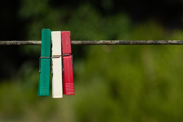 Three clothes pins arranged in the colour of the Italian flag on a clothes line.