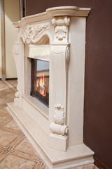 Ornate white stone fireplace with carved corbels and burning fire in classic interior © Olexandr Tytarchuk