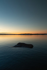 A lone rock in the sea shore during a cold autumn evening.