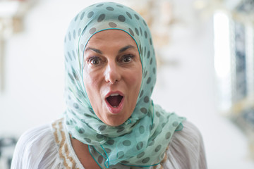 Middle age brunette arabian woman wearing colorful hijab scared in shock with a surprise face, afraid and excited with fear expression