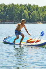 Child boy falling from a paddleboard into the water