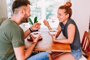 Young couple eating cereal breakfast at dining room table