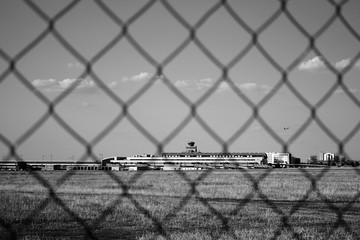 Ruzyne, Czech republic - August 16, 2018: building of Vaclav Havel airport in Prague and flying aeroplane viewed behind fence during summer holiday afternoon