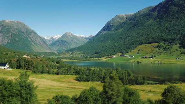 A picturesque Norwegian fjord, on the banks along the water, traditional wooden houses. Idyllic landscape, view from the window of a traveling car