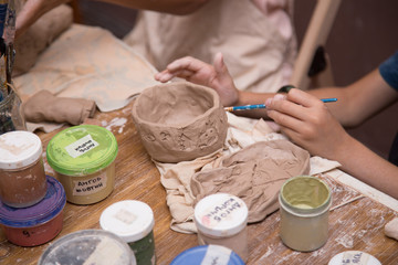 Pottery workshop for kids, raw clay, sculpting tools, glazing and painting clay pots