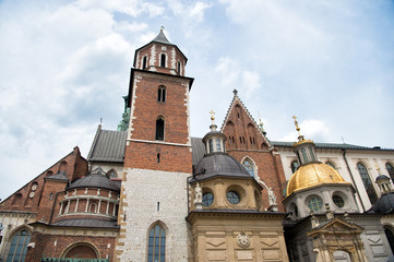 Old city architecture concept. Tower belfry with steeples in Krakow. Architectural heritage. Old or ancient church or cathedral with many window made out of red brick. Tower with cross on top of roof