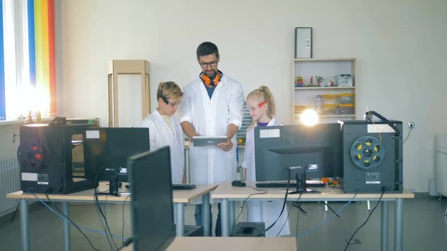 Research worker is showing something on his tablet computer to the children