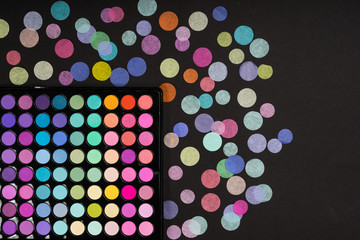 Make-up palette with confetti on black texture