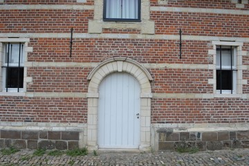 Fototapeta na wymiar Closeup photograph of windows and a white arched door in a historical brick-and-limestone building at Park Abbey, Leuven, Belgium.