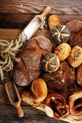 Different kinds of bread and bread rolls on board from above. Kitchen or bakery