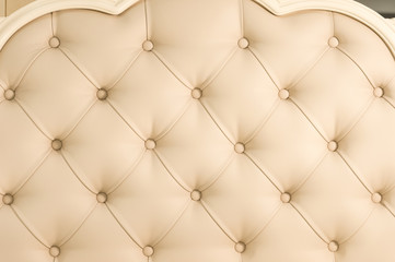 Beige soft tapestry pattern background with symmetrical buttons on the corners of diamonds. Soft and expensive furniture elements. Luxury background