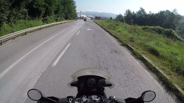 Motorcyclist Rides on a Beautiful Landscape Mountain Road in Austria. First-person view. POV. Mototravel. Viewpoint of a biker riding down a scenic and empty road toward the mountains.