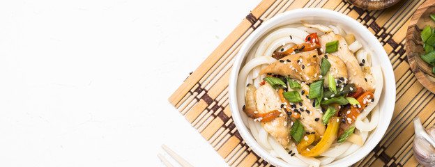 Udon stir-fry noodles with chicken and vegetables on white.