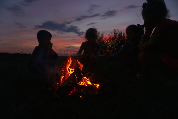 silhouette of children near the fire at sunset