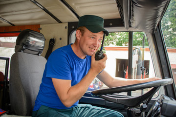 A firefighter in protective clothing sits in a cargo rescue vehicle and talks on the radio © silentalex88