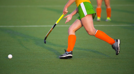 Young hockey player woman with ball in attack playing field hockey game