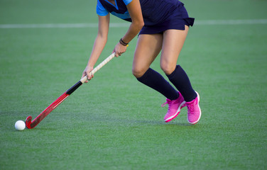 Obraz premium Young hockey player woman with ball in attack playing field hockey game