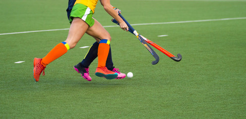 Close up of two field hockey players, challenging eachother for the control and posession of the ball during an intense, competitive match on professional level