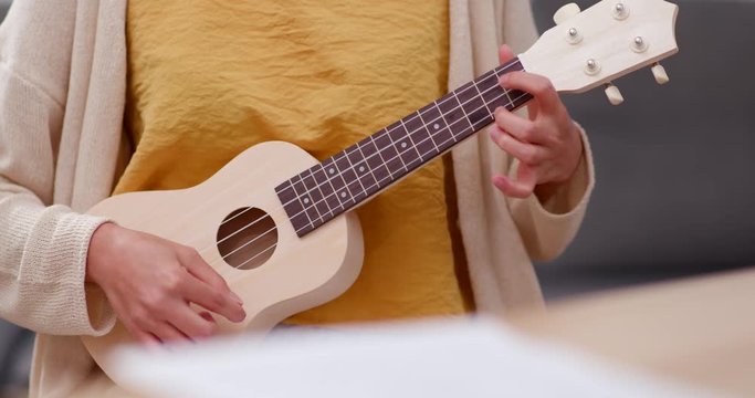 Woman play ukulele at home