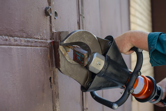 Fire fighter with a hydraulic cutter in his hand cuts the door lock