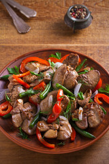 Chicken liver with red paprika, green beans and onion. Sauteed liver with vegetables on a plate. vertical