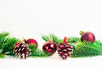 Christmas fir branches with different decoration like scarlet balls, pine cones. On white background.