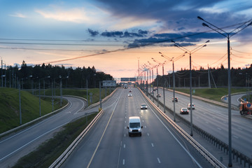 Highway traffic in sunset. minivan on the asphalt road with metal safety barrier or rail. Pine forest on the background
