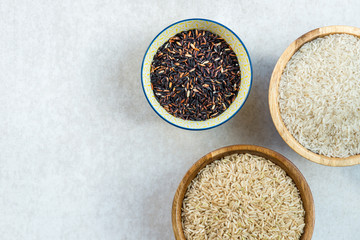 Different types of rice in wooden bowls such as basmati, brown a