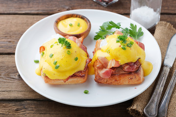 Eggs benedict with bacon on wooden background . 