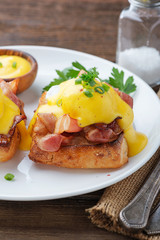 Eggs benedict with bacon on wooden background . 