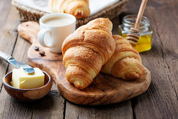 Delicious breakfast with fresh croissants and coffee served with butter and honey. - obrazy, fototapety, plakaty
