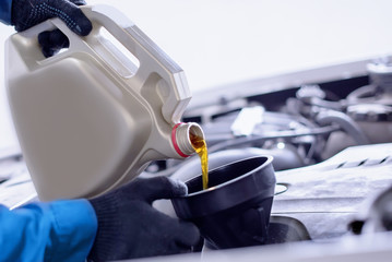 a close-up of the work in the car-care center. replacement of engine oil. The oil flows out of the...
