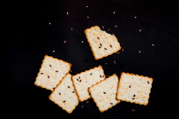 Isolated cracker with sesame seeds and linseeds on a black background