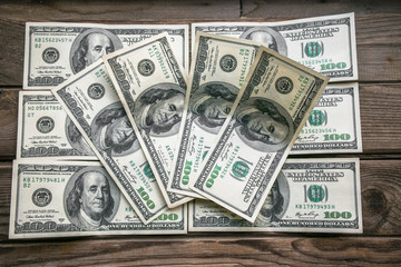 A few 100 dollar bills laid out on an aged wooden surface.