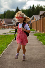 little girl with a backpack run from school