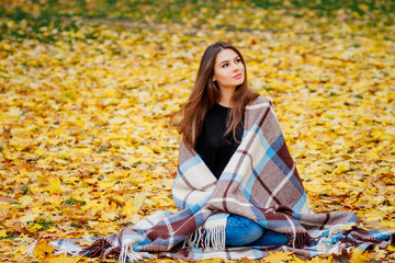 cute girl resting sitting in the Park in autumn, girl in yellow leaves in nature