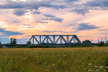 Fototapeta na wymiar Evening sky over the railway bridge and flowered Bogolyubovo meadow, Vladimir region.