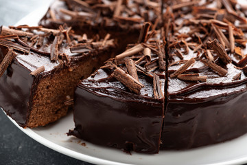 Sliced tasty chocolate cake on wooden background.